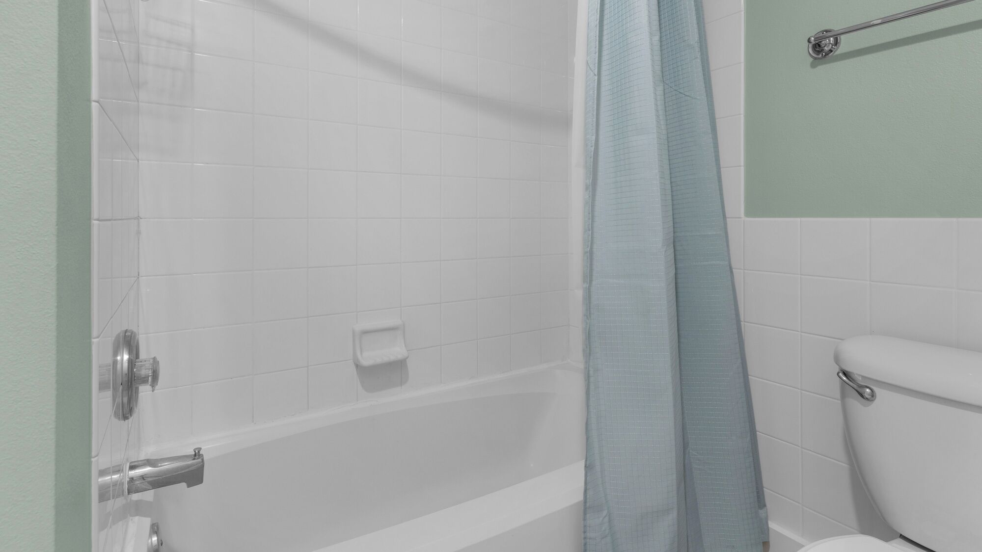 A bathroom with a bathtub, toilet, and a shower curtain.