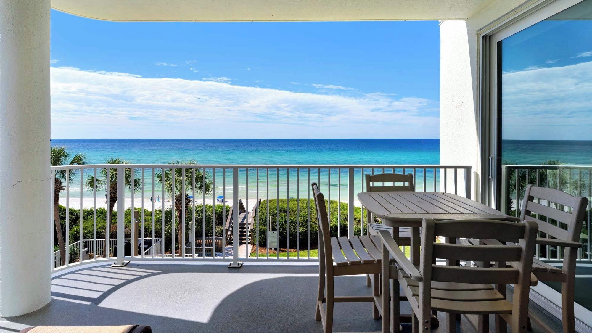Un balcon avec vue sur l’océan, une table et des chaises.