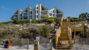 A beachfront property with a multi-level building, a wooden staircase, and a sandy beach area. - Gulf Front, Pool, Modern Design & Amazing Views + Free Attraction Tickets! (Seacrest)