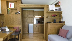 Una cocina compacta con armarios de madera, un refrigerador y un comedor con mesa y sillas.
