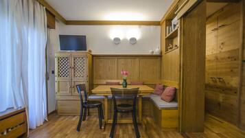 A cozy room with a wooden dining table, chairs, a bench, and a cabinet with a lattice design.