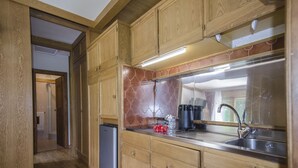 Una cocina con armarios de madera, un lavamanos de acero inoxidable y un refrigerador.