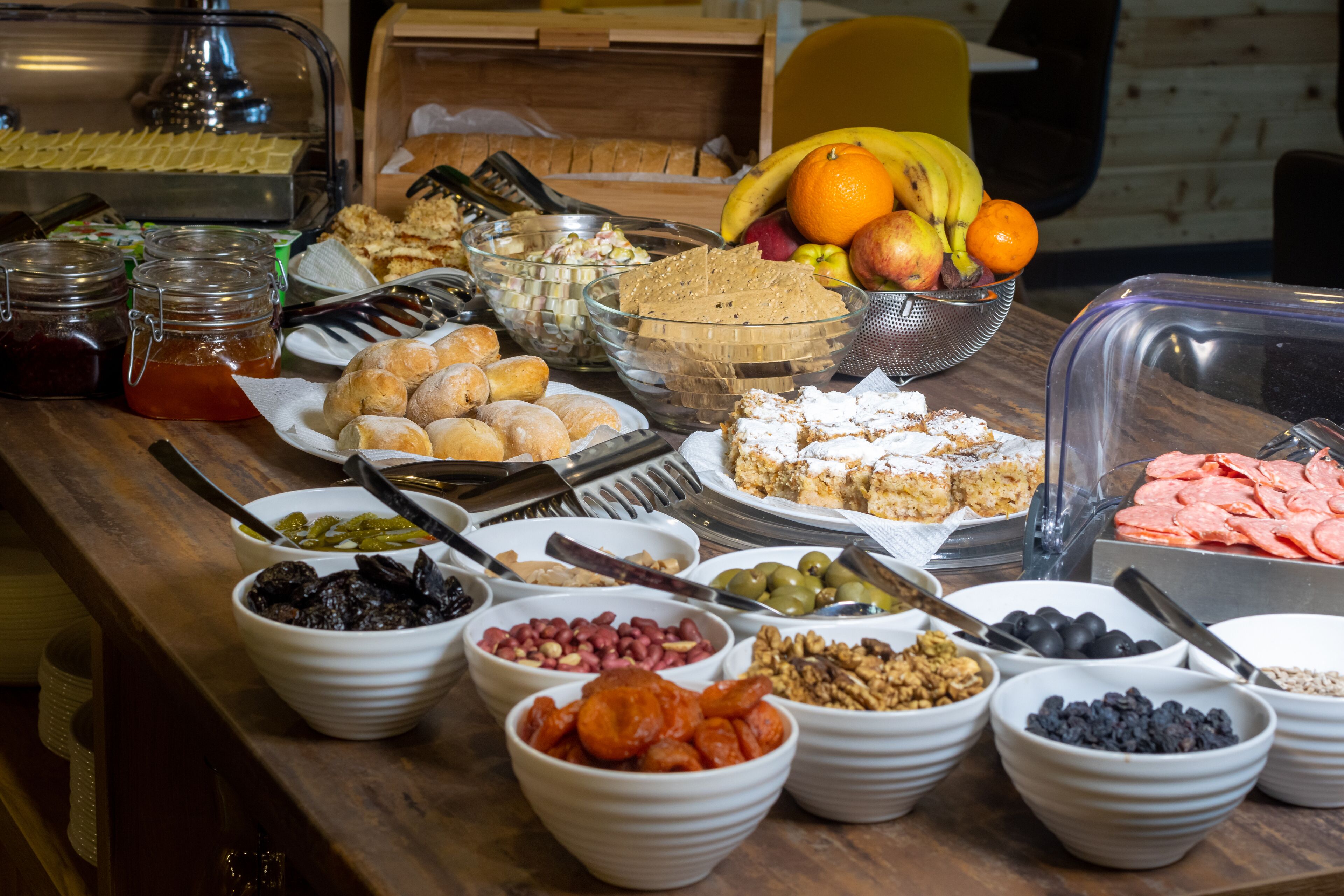 A buffet table with various food items including fruits, pastries, and nuts.