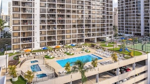 Um hotel com vários andares, piscina no terraço, espreguiçadeiras e garagem.