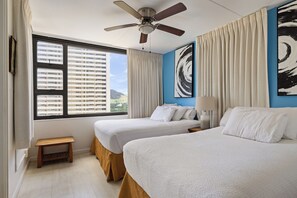 A hotel room with two beds, a ceiling fan, a window with blinds, a small wooden stool, and a painting on the wall. - Spacious 14th Floor Corner Suite, Partial Diamond Head and Ocean Views, FREE Parking! (Honolulu)