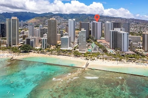A coastal cityscape with high-rise buildings, a beach, and a clear view of the ocean.