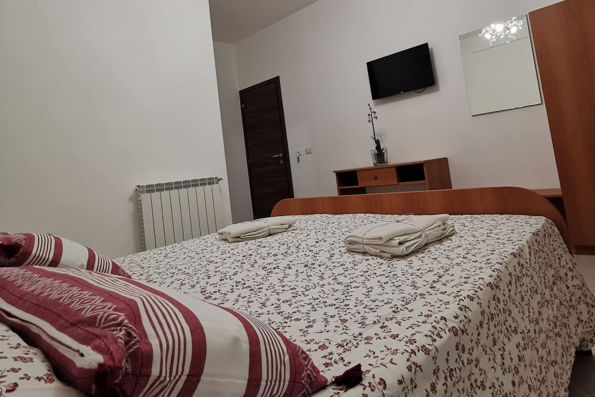 Un dormitorio con cama, televisor, espejo y candelabro.