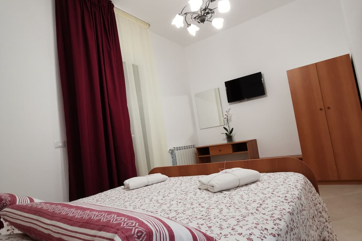 Un dormitorio con cama, televisión, armario y lámpara en el techo.