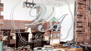 A breakfast buffet with various pastries and baked goods, set against a brick wall with a decorative mirror. - Villa Antonio (Aci Castello)
