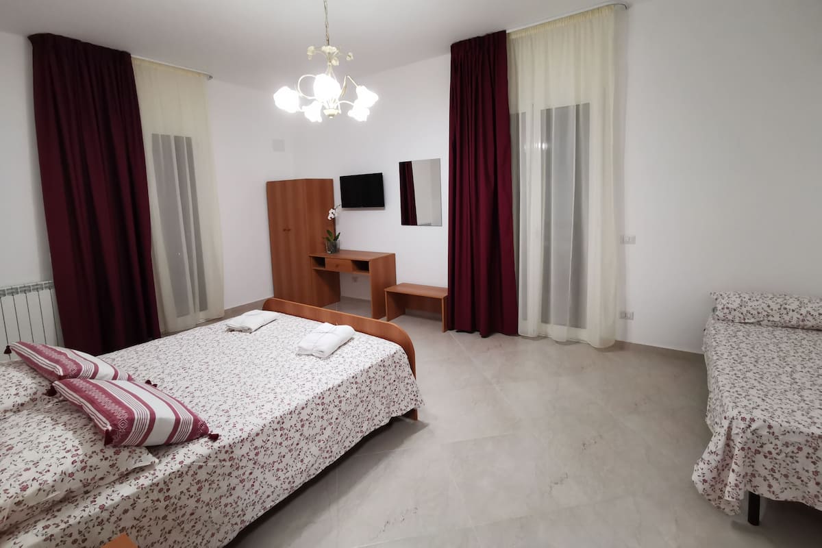 Un dormitorio con cama, escritorio, silla y televisor.