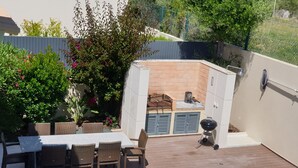 A backyard with a barbecue area, a pool, and outdoor furniture.