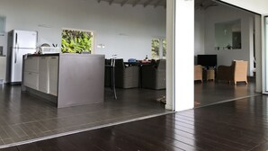 Une cuisine moderne dotée d’un îlot central, d’un réfrigérateur et d’un coin repas avec des meubles en osier.