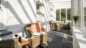 A sunlit patio with wicker furniture, a glass door, and a view of greenery. - NEW 2021, Idyllic Cottage in Polkerris,  by the beach, sea views, near Fowey. (Par)