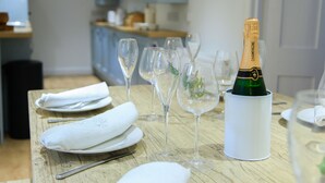 A dining table with wine glasses, a bottle of champagne, and white napkins. - NEW 2021, Idyllic Cottage in Polkerris,  by the beach, sea views, near Fowey. (Par)