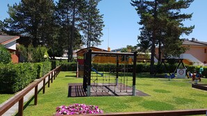 A playground with a climbing structure, a slide, and a fenced area.