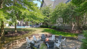 Une terrasse avec des fauteuils Adirondack, un foyer et une piscine en arrière-plan.