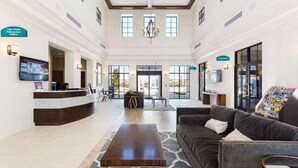 A spacious lobby with a reception desk, seating area, and a chandelier.