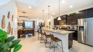 A modern kitchen with dark cabinets, stainless steel appliances, and a central island with bar stools.