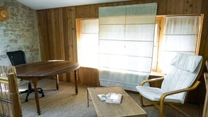 A room with a wooden dining table, a wicker coffee table, a wooden chair, and a cushioned chair. - abundance, Stone house with land of 2000m2 at the foot of the vercors (La Baume-Cornillane)