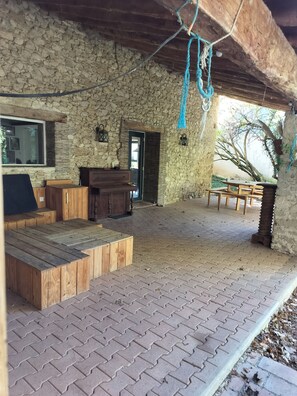 A rustic stone building with a wooden bench, a table, and a door leading outside. - abundance, Stone house with land of 2000m2 at the foot of the vercors (La Baume-Cornillane)