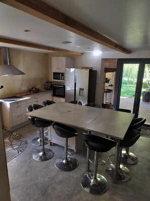 A modern kitchen with a large island, built-in appliances, and a dining area with bar stools. - abundance, Stone house with land of 2000m2 at the foot of the vercors (La Baume-Cornillane)