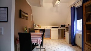 Une cuisine compacte comprenant un coin repas, un four à micro-ondes, une machine à café et une fenêtre avec des rideaux.