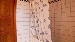 Une salle de bain avec des murs recouverts de carreaux blancs et une porte en bois.