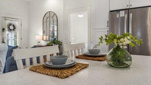 Eine moderne Küche mit einem Edelstahl-Kühlschrank, einem Esstisch mit Blumenvase und einer weißen Bank.