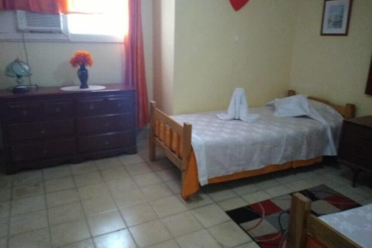 Ein Schlafzimmer mit Bett, Schminktisch, Schreibtisch und einem Fenster mit Vorhängen.