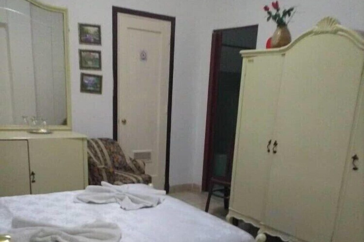 Ein Schlafzimmer mit Bett, Kleiderschrank, Spiegel und Tür.