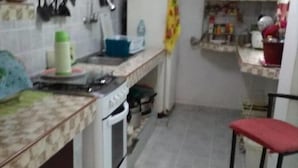 Una piccola cucina con elettrodomestici essenziali, un bancone e uno sgabello.