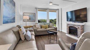A spacious living room with a fireplace, a large TV, and a view of the outdoors. - Private Beach Access + Free Seasonal Beach Chairs & Attraction Tickets! (Santa Rosa Beach)