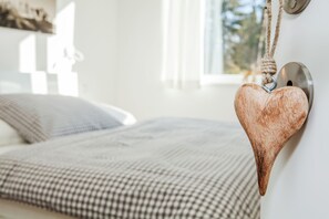 A bed with a checkered blanket and a heart-shaped decoration hanging from the wall. - Quartier39 (Sankt Johann in Tirol)