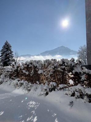 A snowy landscape with a mountain in the background, a clear sky, and a building with a tiled facade. - Quartier39 (Sankt Johann in Tirol)