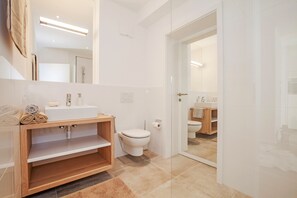 A modern bathroom with a wooden vanity, a toilet, and a glass shower enclosure. - Quartier39 (Sankt Johann in Tirol)