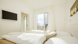 A bedroom with a bed, a TV mounted on the wall, and a window with curtains. - Quartier39 (Sankt Johann in Tirol)