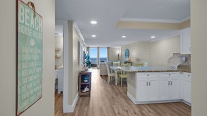 A spacious kitchen with white cabinets, a granite countertop, and a view to the outside.