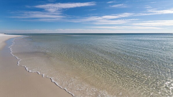 A beach with clear shallow waters and a sandy shore.
