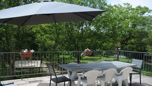 Eine Terrassenausstattung mit Tisch und Stühlen, umgeben von einem Metallgeländer.