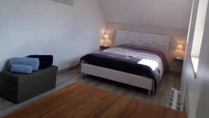 Ein Schlafzimmer mit einem Bett, Nachttischen, einer Bank und einem Bild an der Wand.
