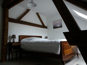 Un dormitorio con estructura de cama de madera, una mesita de noche, una lámpara y una luz de techo.