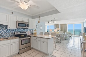 A modern kitchen with white cabinets, stainless steel appliances, and a large island with bar stools.