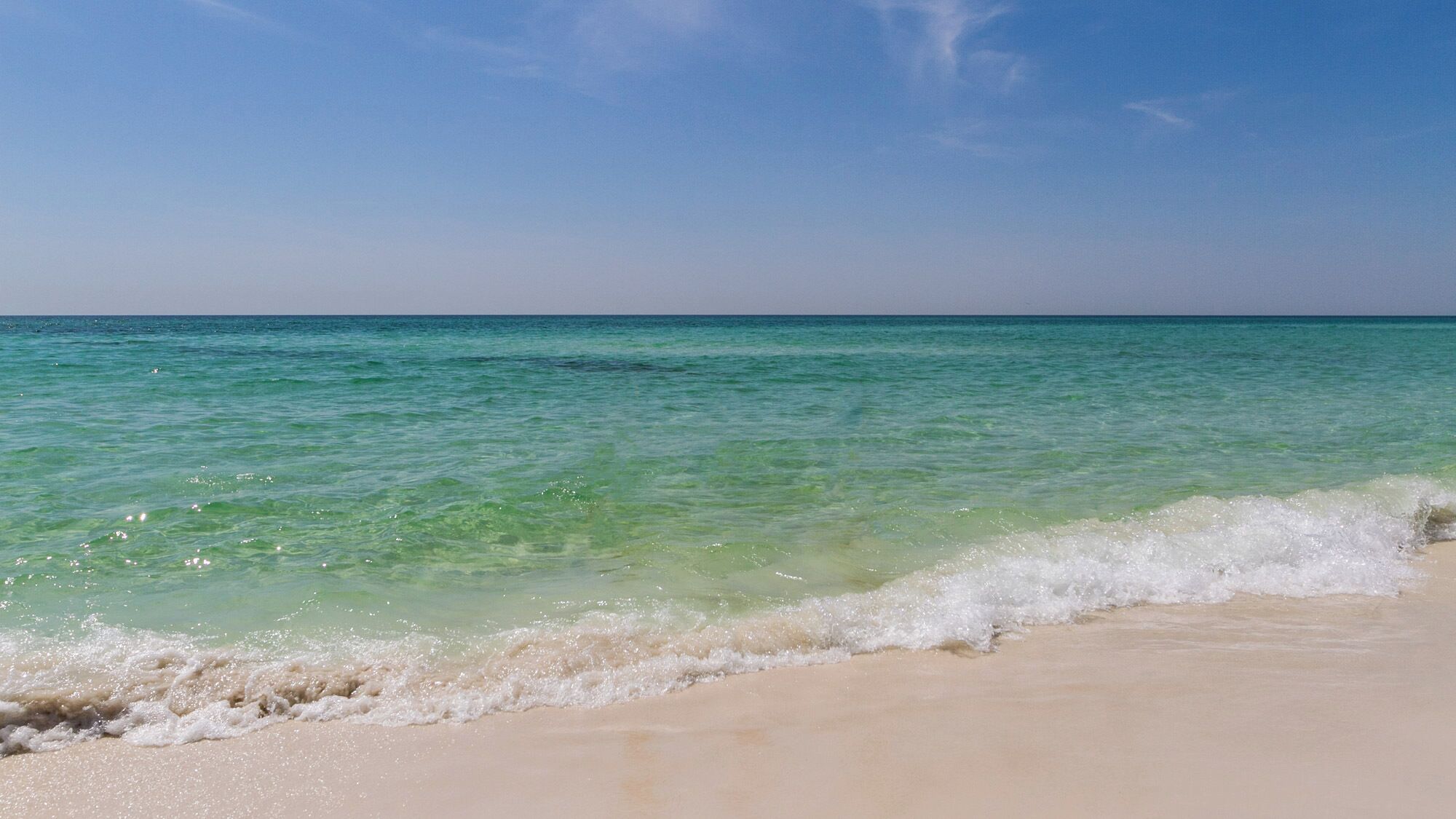 Een strand met helder turquoise water en een zandstrand.
