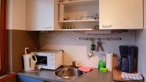Ett kök med mikrovågsugn, brödrost, diskho och kaffebryggare.