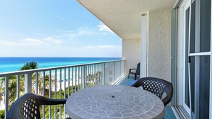 Ein Balkon mit Blick auf das Meer, einem runden Tisch und zwei Stühlen.
