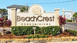 Schild für BeachCrest Condominiums mit Sonnendesign und Palmenmotiv.