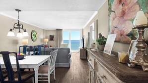 A hotel room with a dining area, a sofa, a TV, and a view of the ocean. - Gulf-front condo, Private Beach, Pool w/ beach chairs & attraction tickets! (Santa Rosa Beach)