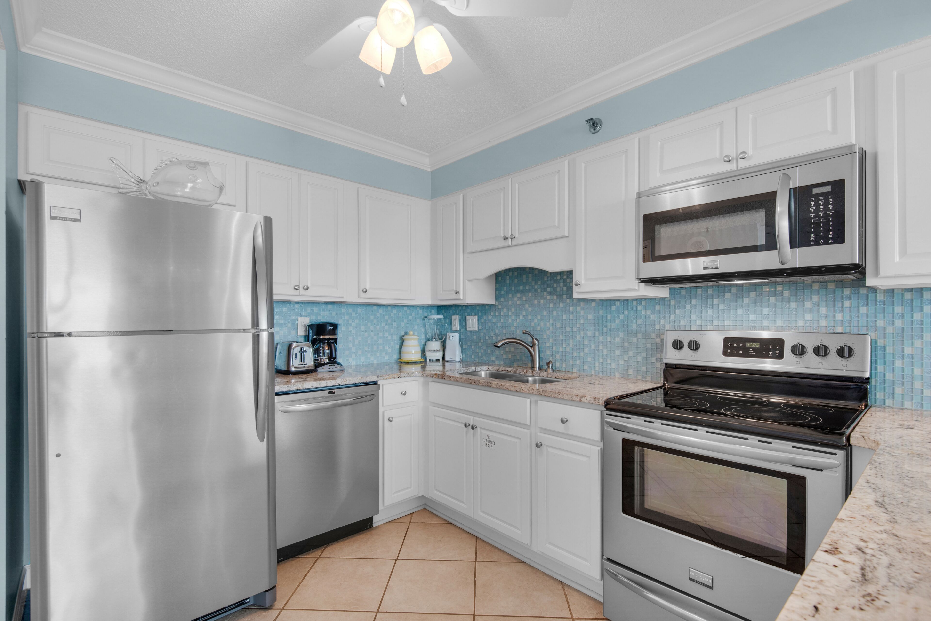A kitchen with white cabinets, a stainless steel refrigerator, a microwave, a stove, and a dishwasher.