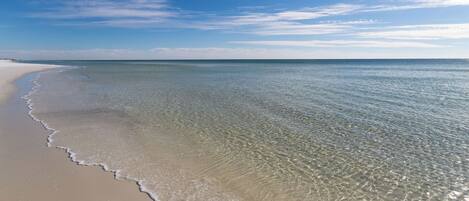 Una playa con aguas poco profundas y cristalinas y una orilla arenosa.