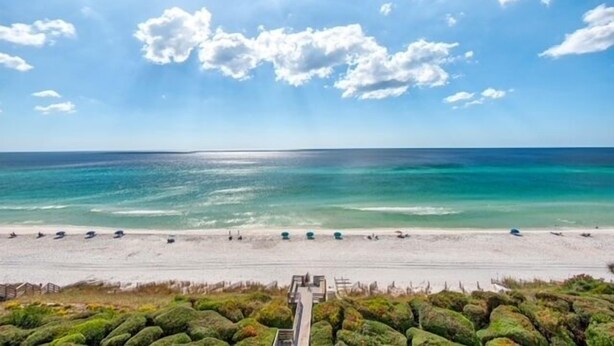 Ein Strand mit blauem Himmel, ruhiger See und einem Weg zum Ufer.